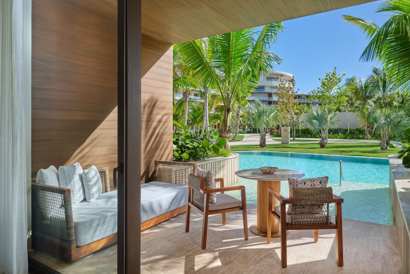 A suite terrace beside the pool at St Regis Cap Cana, with woven chairs and a private table
