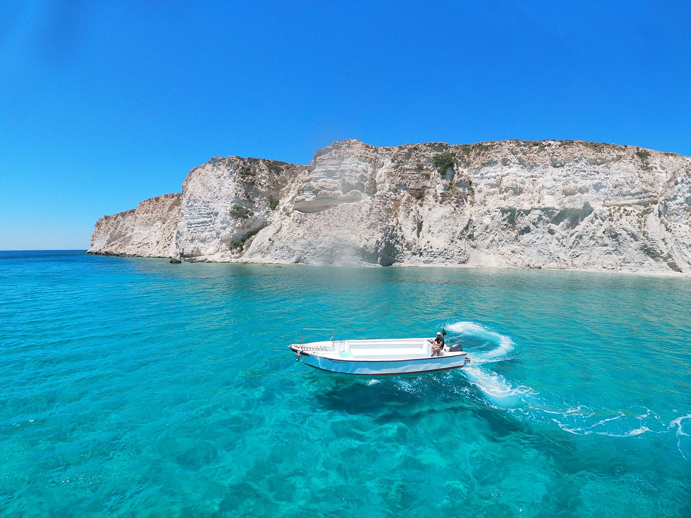 A small boat on the clear turquoise water off a Greek island