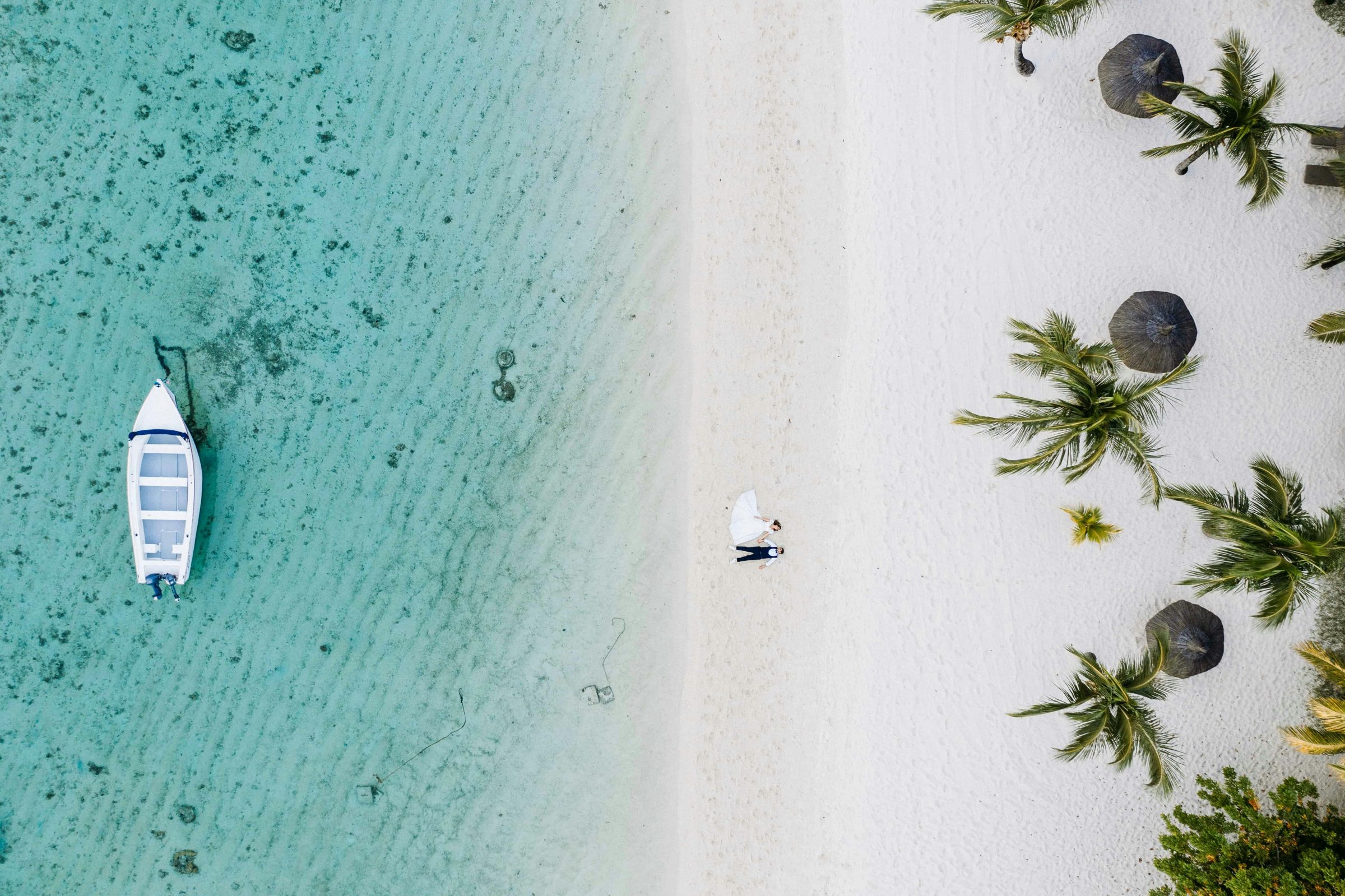 A boat on the lagoon beside a pale-sand beach and palms, Belle Mare, Mauritius