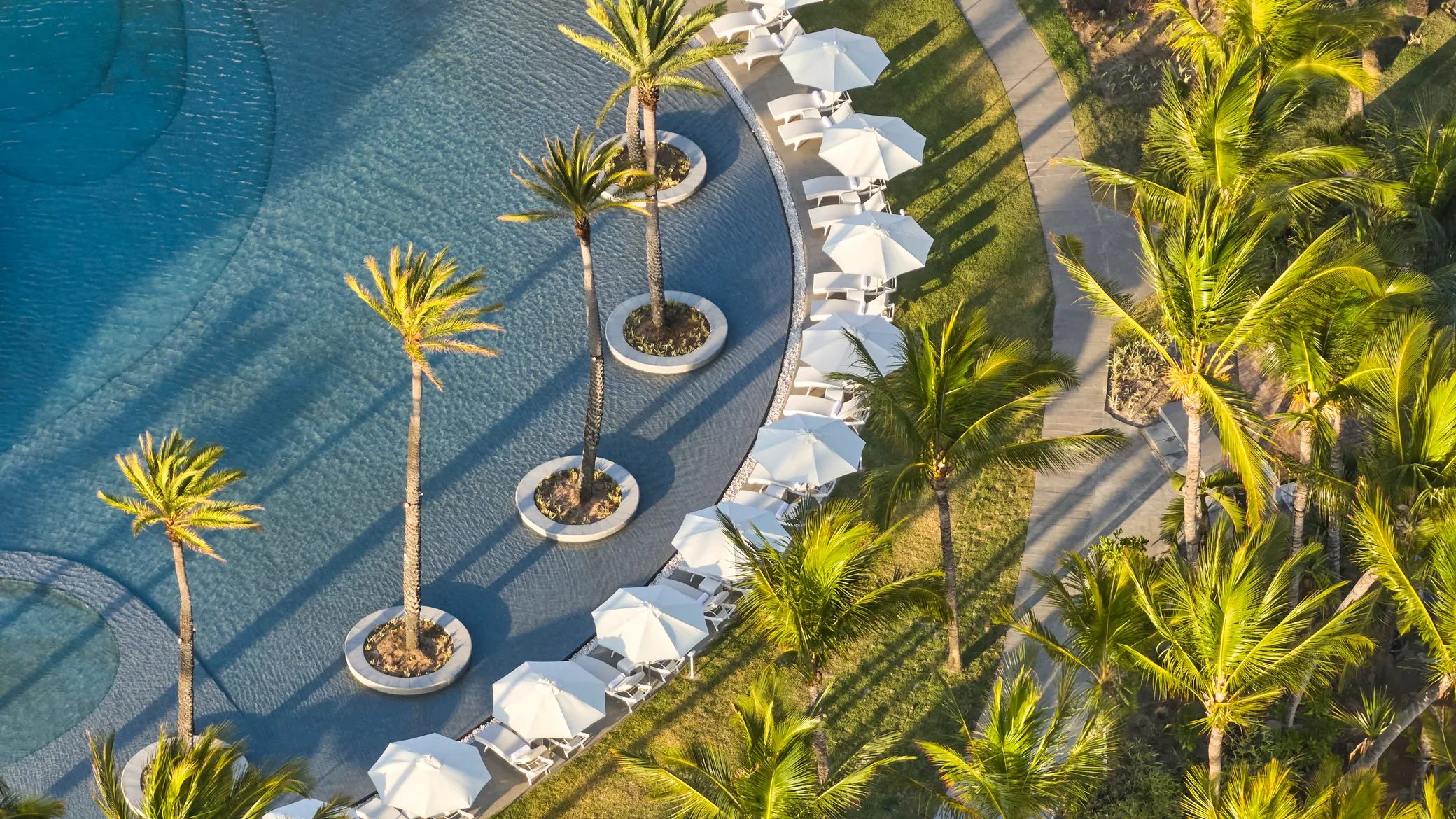 Aerial of palm-dotted pool and loungers, LUX* Belle Mare, Mauritius