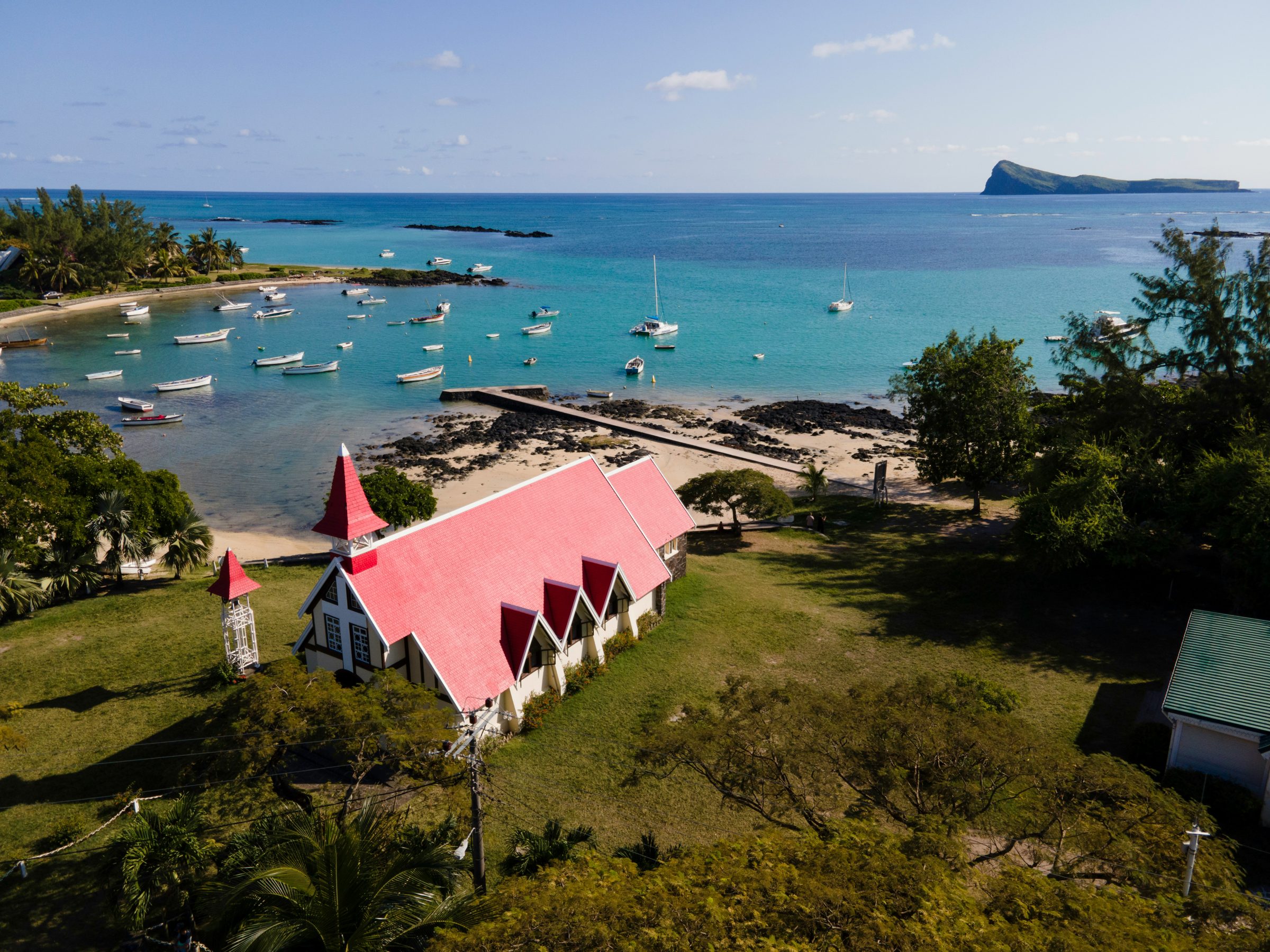 The red-roofed Cap Malheureux chapel, boats and an offshore islet, the north of Mauritius